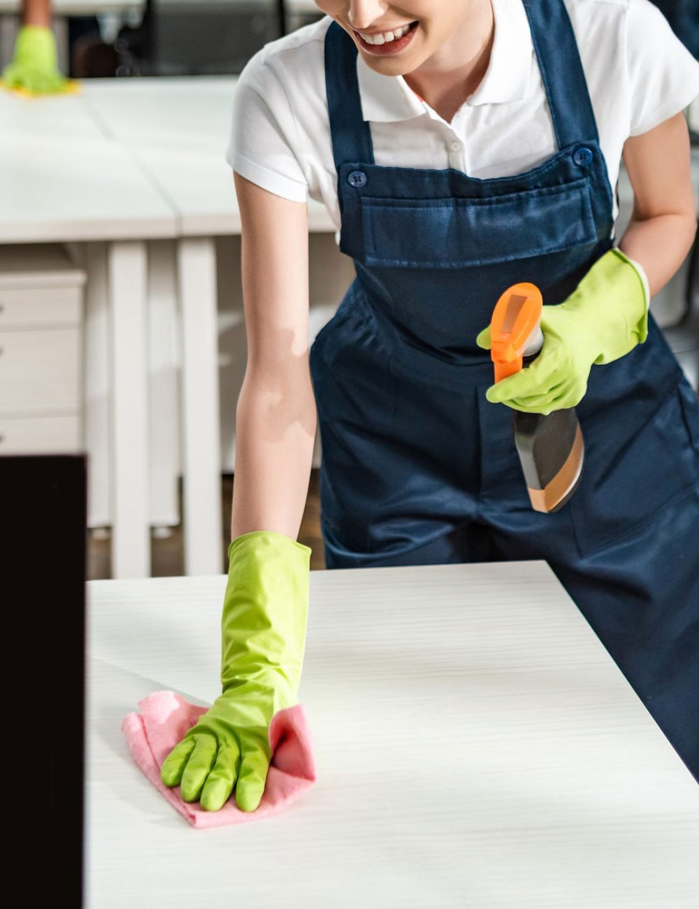 cheerful-cleaner-in-overalls-cleaning-office-desk-with-rag-1